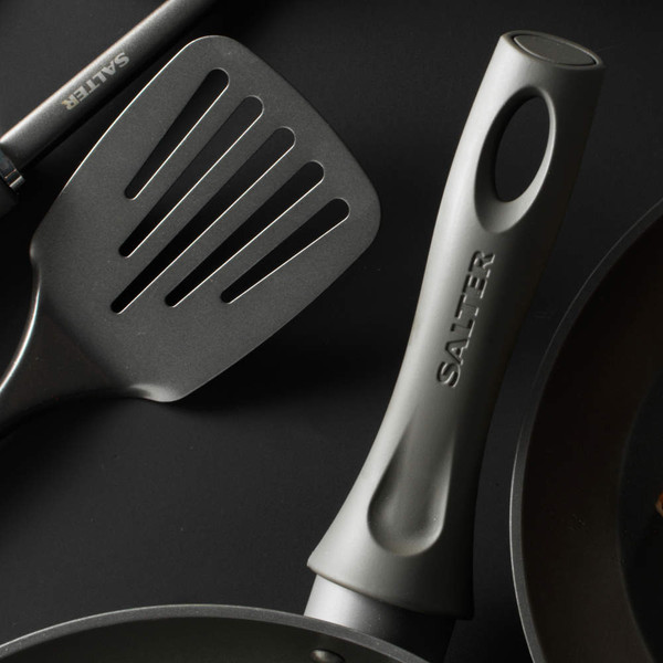Close-up of grey Salter frying pan handle and spatula on dark background