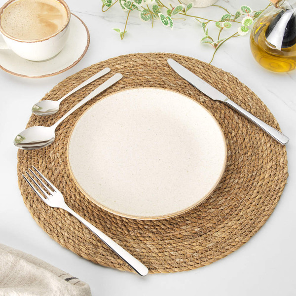Hand holding fork with slice of sponge cake on cream stoneware plate, with coffee and cutlery