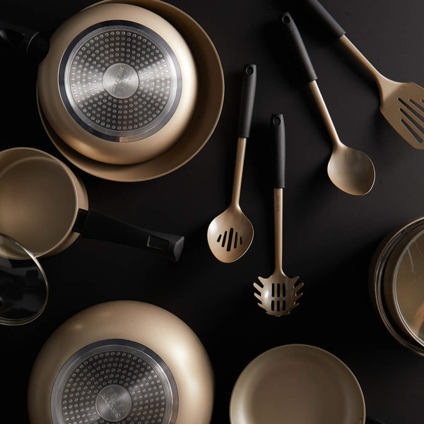 Gold non-stick cookware and utensils set on black background