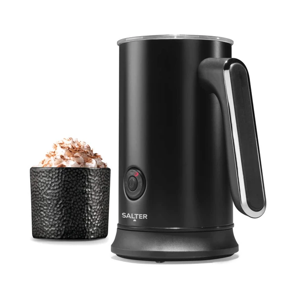 Black electric milk frother with handle next to cup of frothed hot chocolate