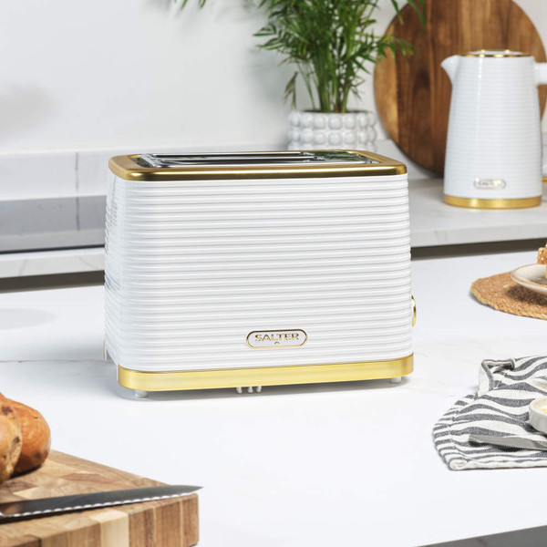 White and gold two-slice toaster on kitchen counter, modern ribbed design.