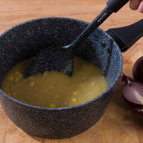 Black speckled Salter saucepan with soup being stirred, shown on a wooden worktop