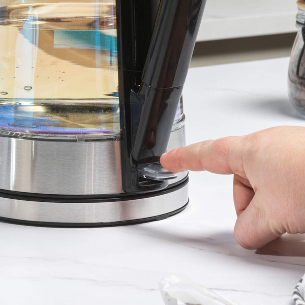Hand pressing button on stainless steel electric kettle base