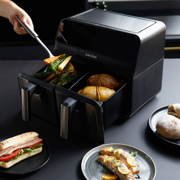 Black Salter dual air fryer with drawers, cooking chicken and vegetables on a kitchen counter