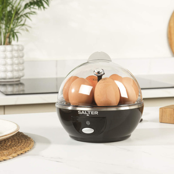 Black electric egg boiler with seven brown eggs on a kitchen counter