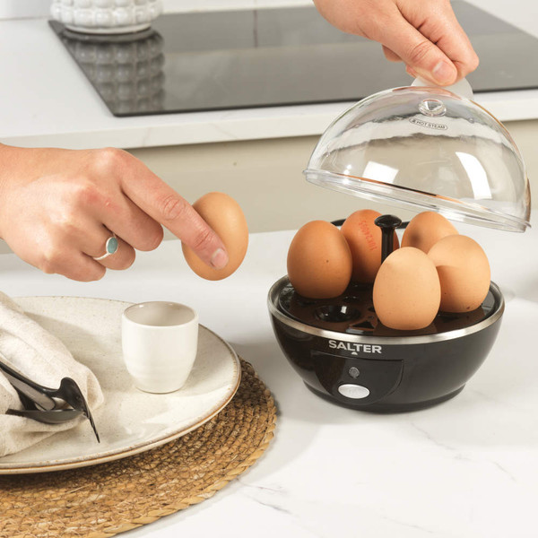 Salter electric egg cooker in black with six brown eggs and a poaching tray.