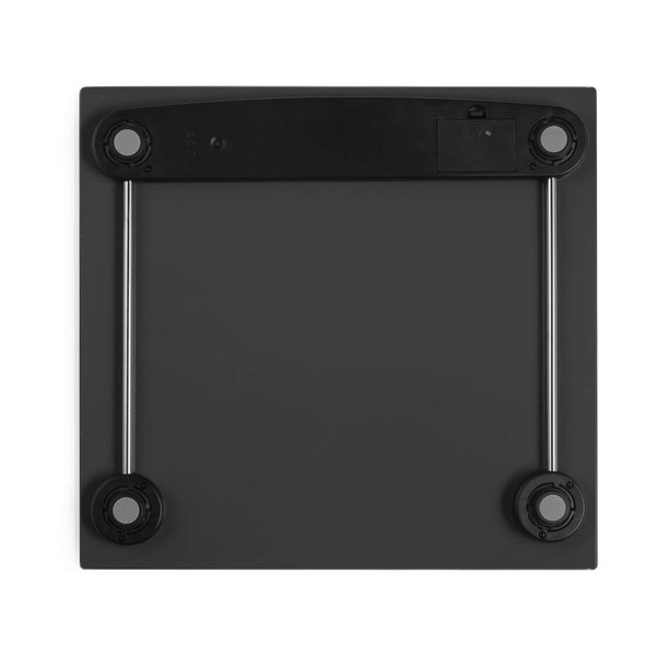 Black digital bathroom scale, underside view showing four round feet and battery compartment