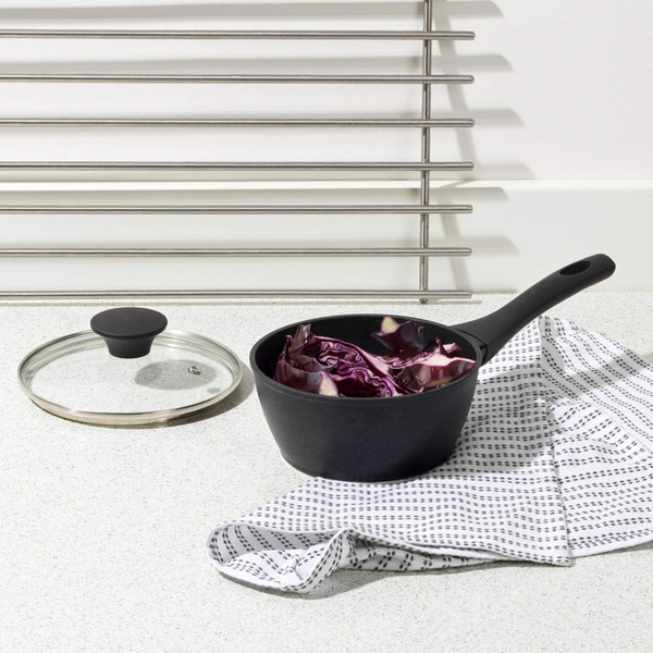 Black saucepan with glass lid, containing chopped red cabbage on kitchen worktop
