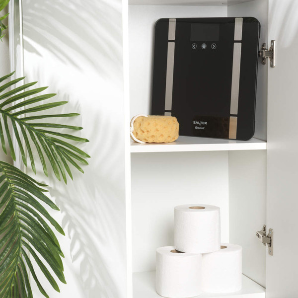 Black smart bathroom scale with phone displaying health app, purple mat and kettlebell nearby