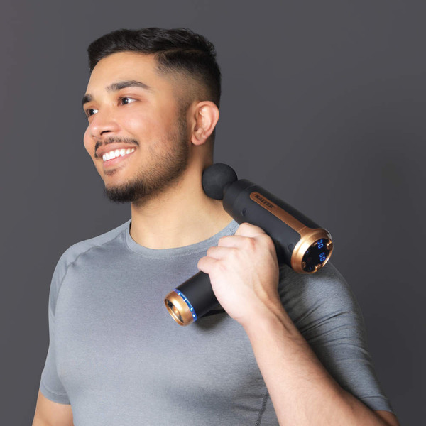 Black and gold massage gun used on shoulder, shown from front