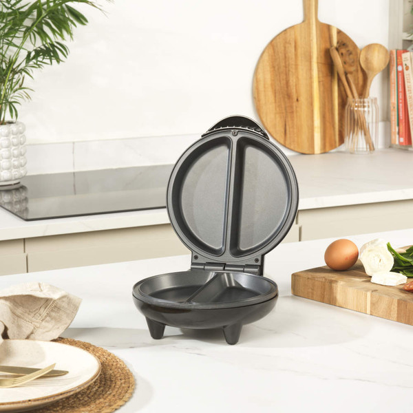 Electric omelette maker with cooked omelettes, surrounded by fresh ingredients on kitchen counter