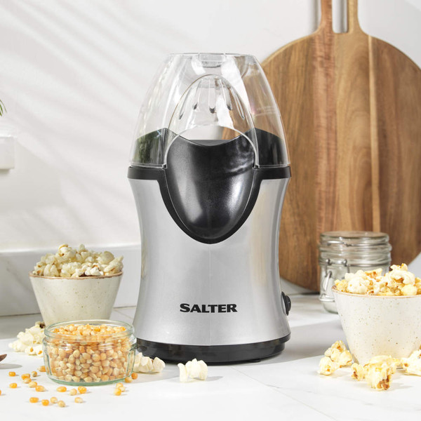 Hand pouring popcorn kernels into a clear electric popcorn maker