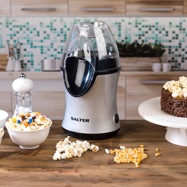 Salter hot air popcorn maker in silver on kitchen worktop, with popcorn, kernels and a chocolate popcorn cake