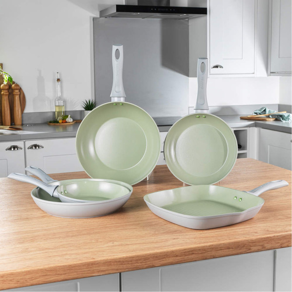 Set of four light green non-stick frying pans and grill pan on kitchen counter