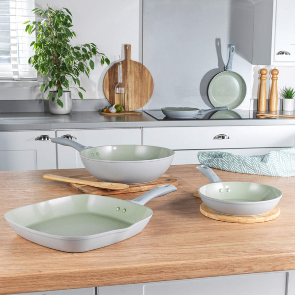 Set of three light grey non-stick frying pans in a kitchen setting