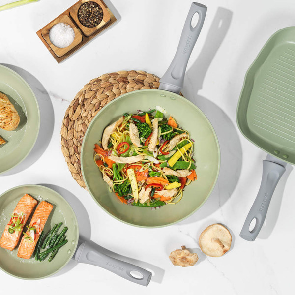 Set of four light green non-stick frying and grill pans on kitchen counter