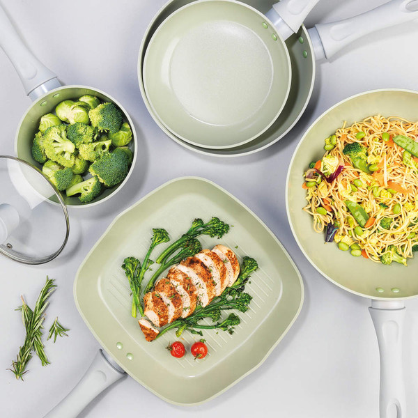 Set of pale green non-stick pans with broccoli, noodles, and grilled chicken.