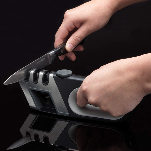 Manual knife sharpener in use, showing hands sharpening a kitchen knife
