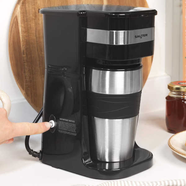 Scoop of ground coffee being poured into a coffee maker filter basket