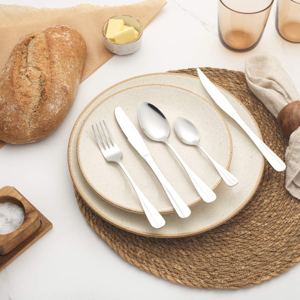 Table setting with cream stoneware plate, woven placemat, linen napkin and silver cutlery