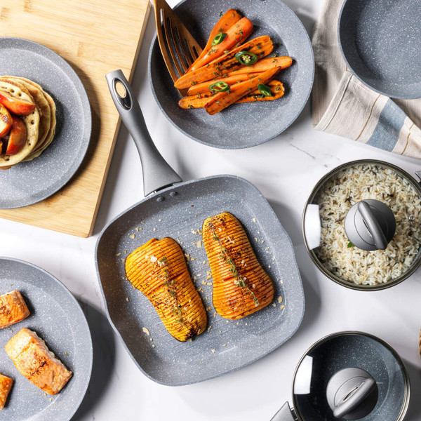 Non-stick grey cookware set with food, including grilled butternut squash, carrots, pancakes, salmon, and rice.