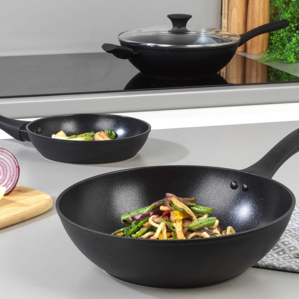 Vegetable stir fry with udon noodles in black wok, featuring broccoli and peppers