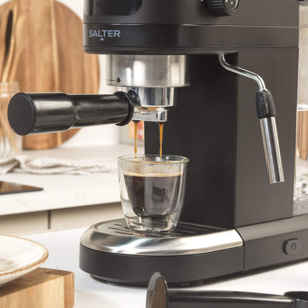 Black Salter espresso coffee machine pouring coffee into glass cup on kitchen counter