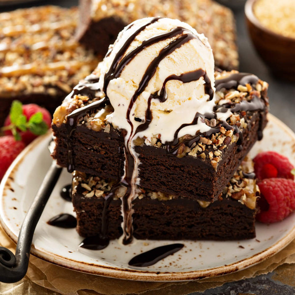 Chocolate brownie topped with vanilla ice cream and chocolate sauce, served with raspberries
