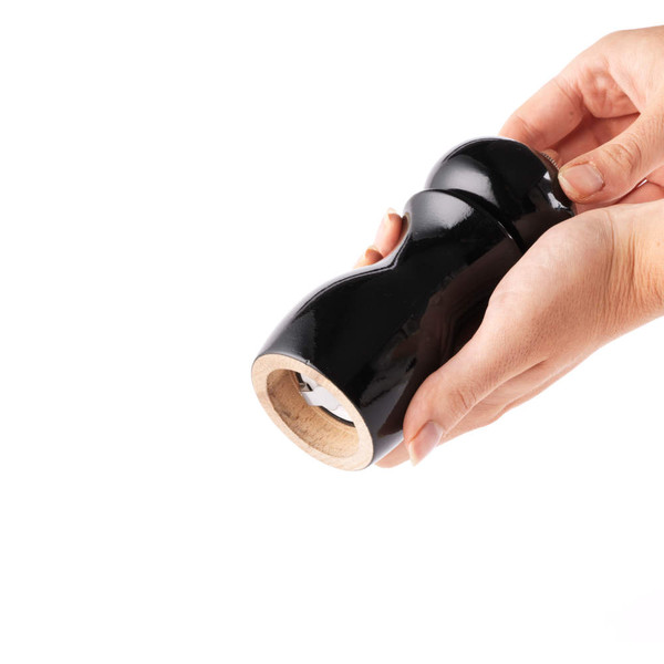 Black wooden pepper mill held in both hands, showing the grinder underside.
