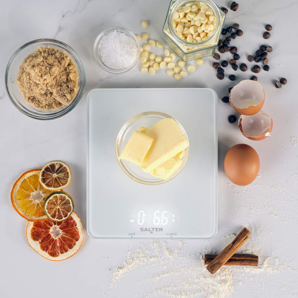 White digital kitchen scale on counter with baking ingredients in background