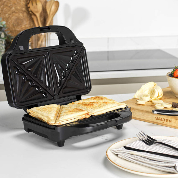 Black waffle maker open on kitchen counter with golden waffles inside