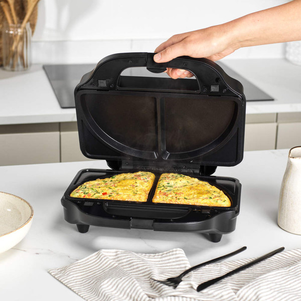 Black waffle maker with two cooked square waffles on kitchen worktop