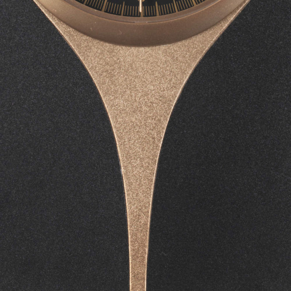 Close-up of modern black and gold clock with textured gold detail below clock face