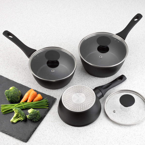 Black saucepan set with glass lids on kitchen counter, shown with cooked potatoes.