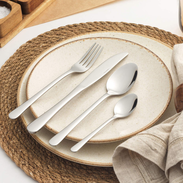 Set of four silver stainless steel cutlery pieces on stone-coloured plate, fork, knife, spoon, teaspoon