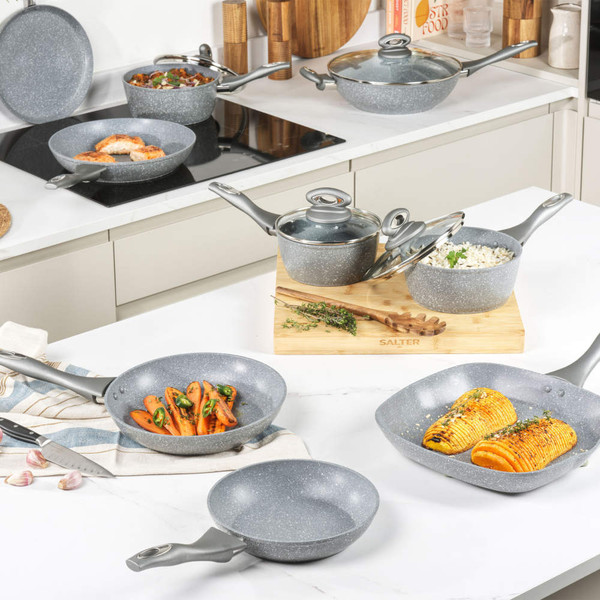 Set of grey non-stick pans and pots with food, shown in a modern kitchen