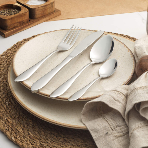 Set of four stainless steel cutlery pieces on cream stoneware plates
