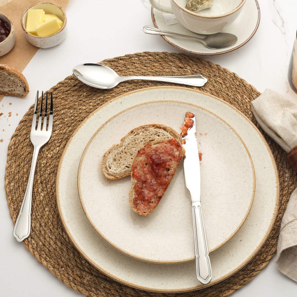 Stainless steel knife, fork, and spoon set on a plate with bread and jam for breakfast.