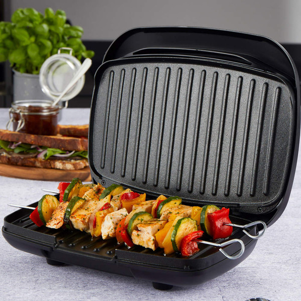 Electric grill with open lid cooking chicken and vegetable kebabs