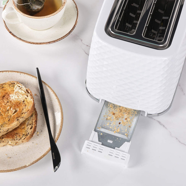 White 2-slice toaster with diamond pattern, crumb tray open, shown beside plate of toast and tea.