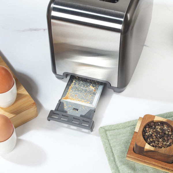 Gunmetal toaster with removable crumb tray extended for cleaning, shown on kitchen worktop.