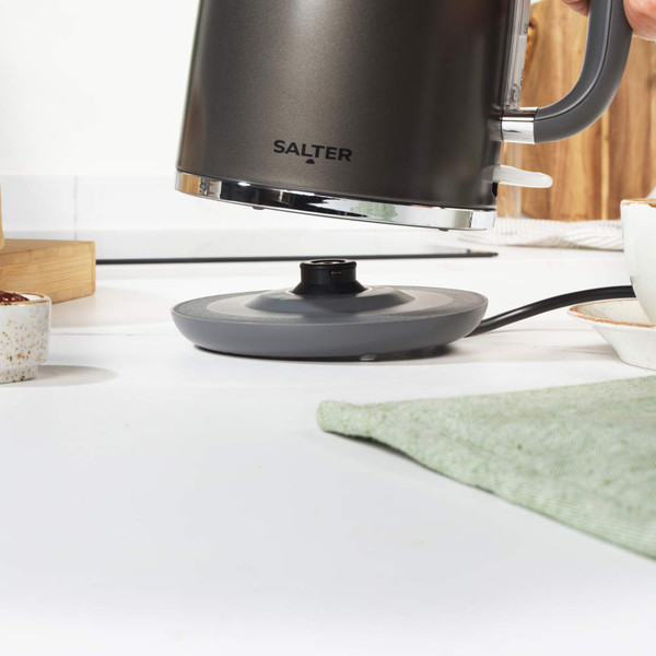 Grey electric kettle pouring hot water into matching mug