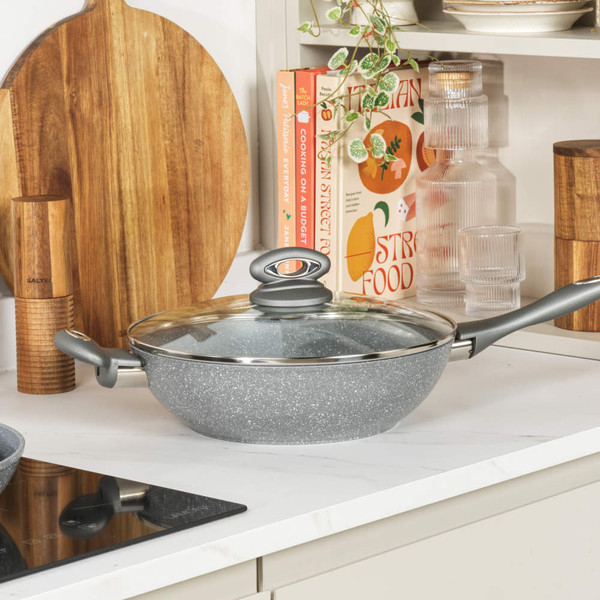 Grey non-stick frying pan with glass lid on kitchen counter