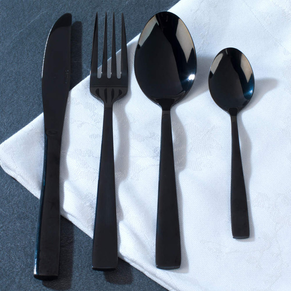 Four-piece black cutlery set on white napkin: knife, fork, dessert spoon, teaspoon