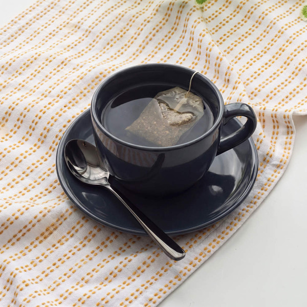 Hand drying a black slotted spoon over a kitchen sink