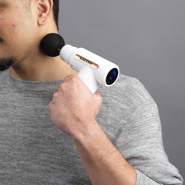 Handheld white massage gun with black round attachment in use, Salter branding visible.