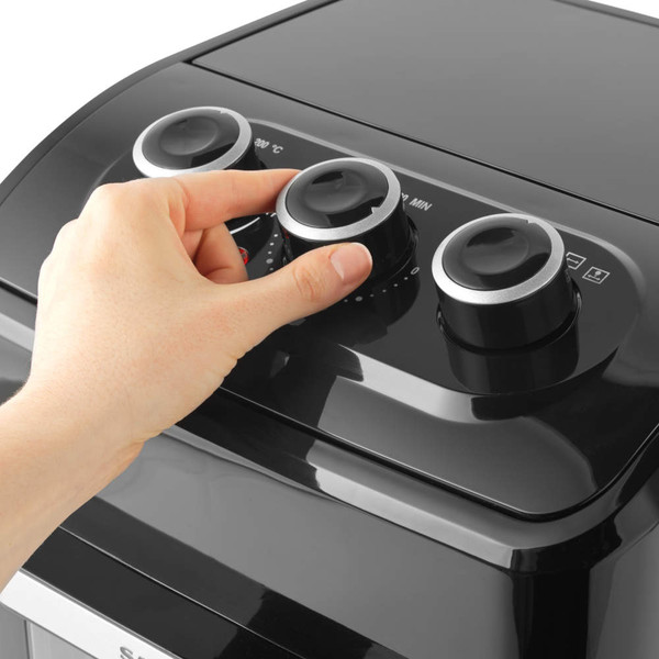 Hand adjusting control dial on black air fryer