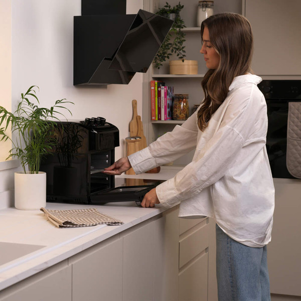 Person using black countertop air fryer in modern kitchen