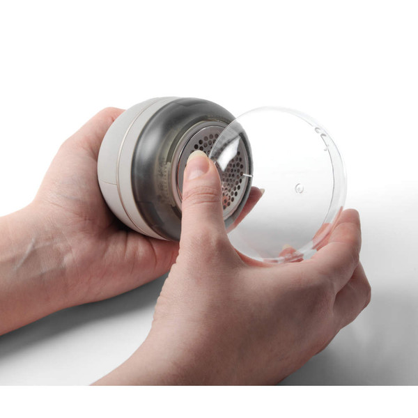 Clothes fabric shaver with clear protective cap held in hands