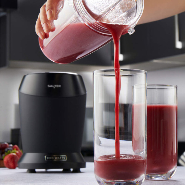 Black Salter blender in kitchen with red smoothie being poured into tall glass